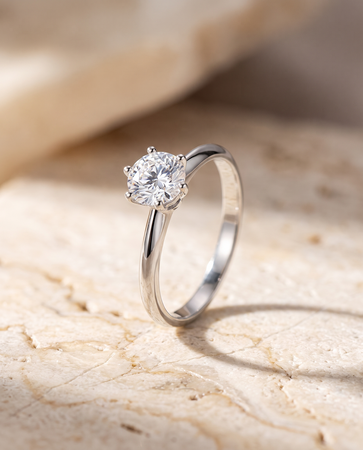 Silver moissanite solitaire ring on warm travertine stone