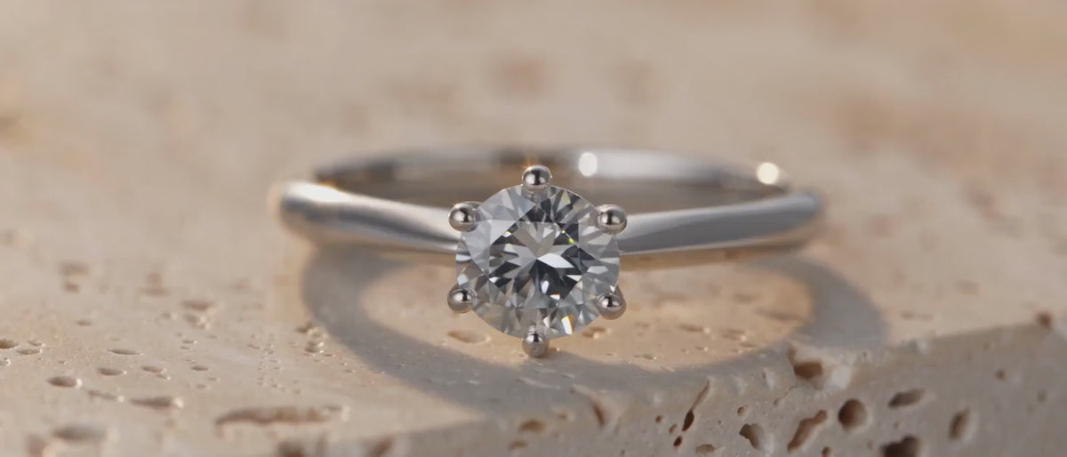 Moissanite solitaire ring on travertine with visible rainbow fire